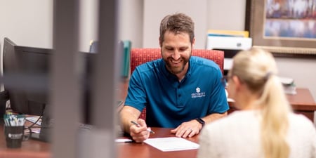Kevin Hegland, senior lending officer for Carver County at Security Bank & Trust Co., reviewing a document with a customer at his desk