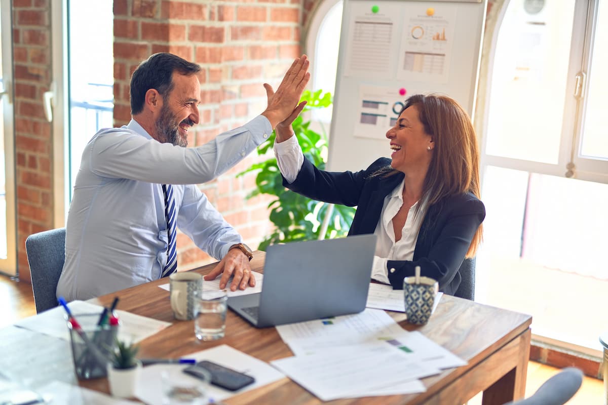 High Five man and women at work at desk - Unsplash