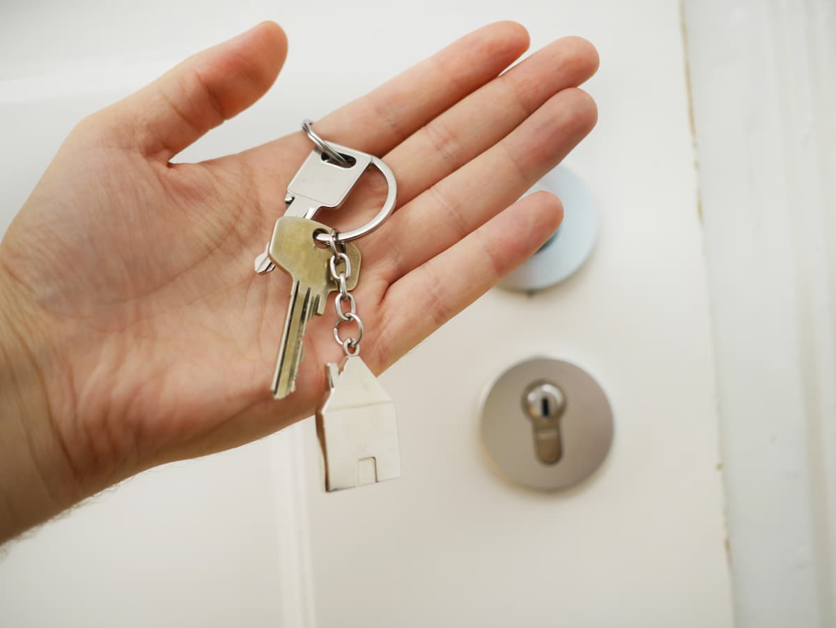 House keys held in an open hand in front of a front door, the asset most often left out when funding a trust in Minnesota