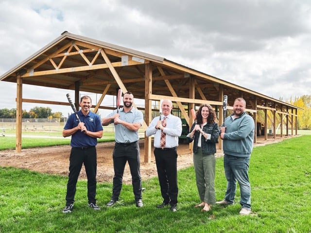 Five people holding baseball bats in front of the new pavilion at the Glencoe Silver Lake softball fields