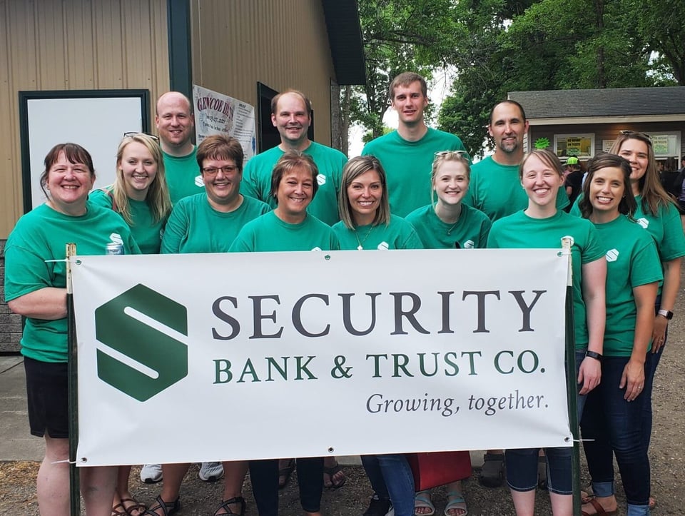 Security Bank & Trust Co. employees in green shirts holding the bank banner at Glencoe Days