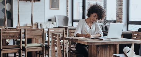 Minnesota woman writing investment goals on a notepad at a table, planning her real estate strategy.