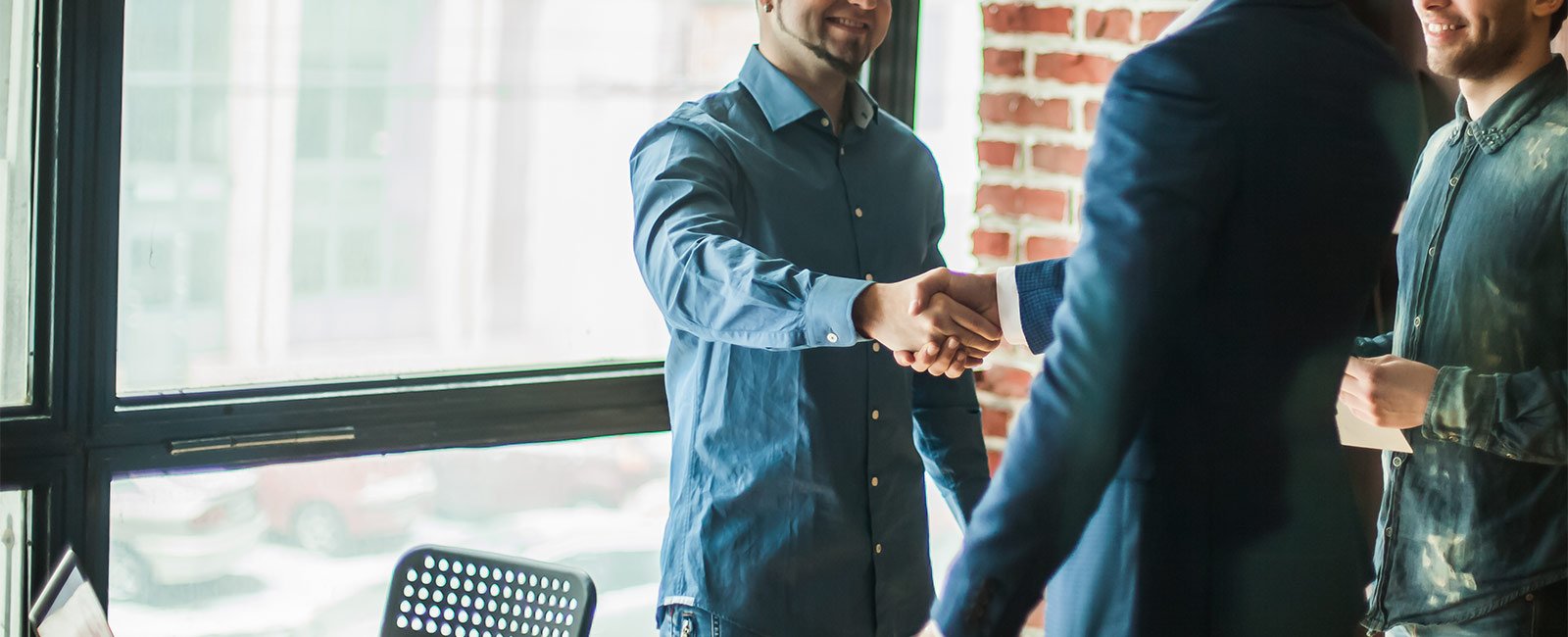 A business owner and a commercial lender shaking hands in a brick office building