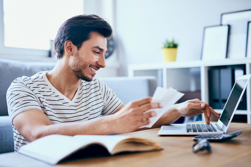 smiling man reading reports while on computer