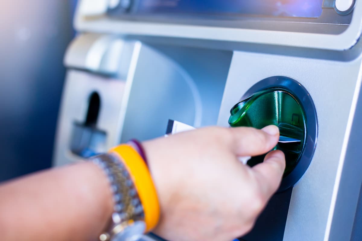 person inserting their bank card into an ATM