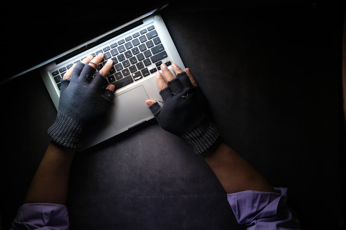 person wearing fingerless gloves accessing a laptop