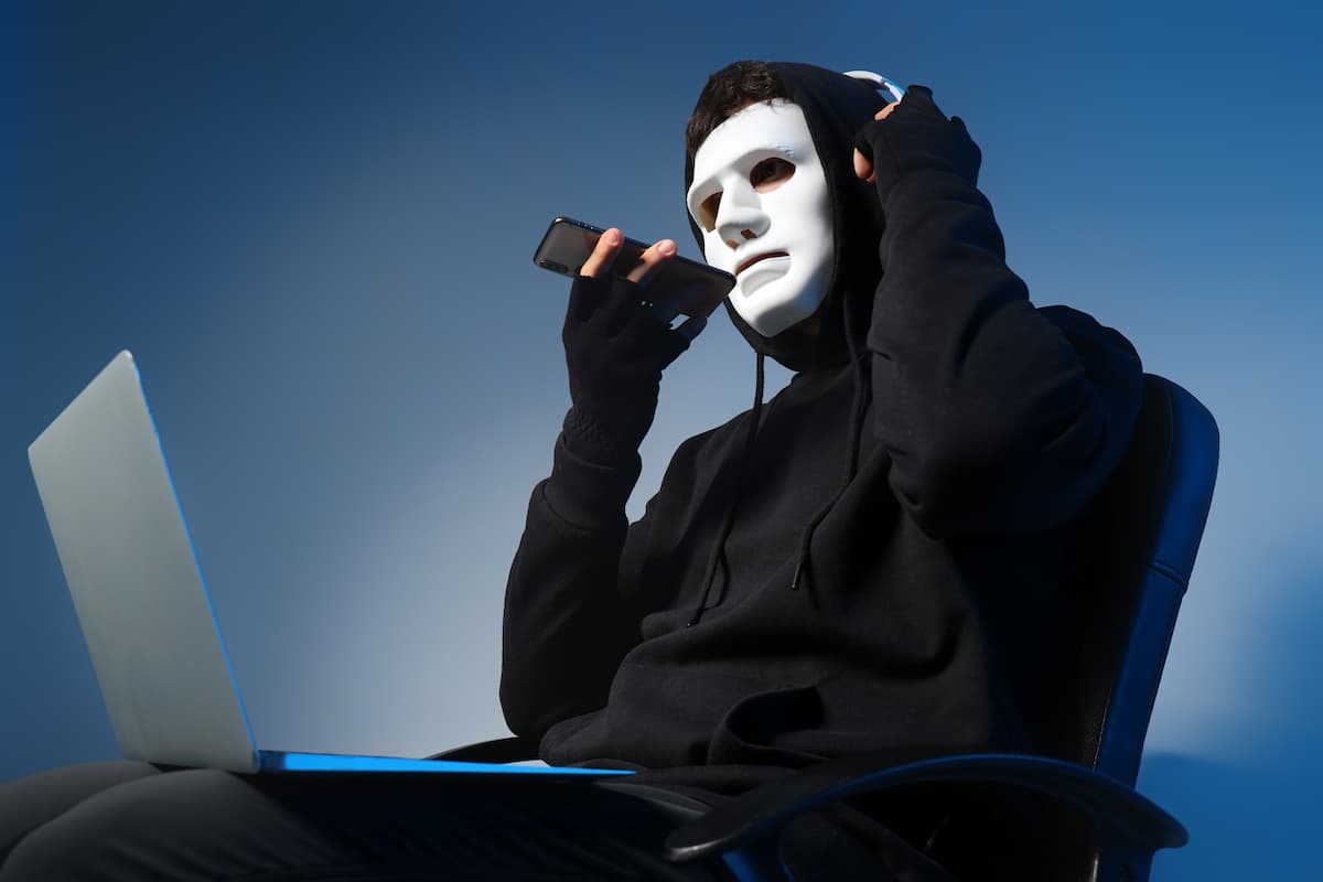 anonymous person in a white mask making a phone call