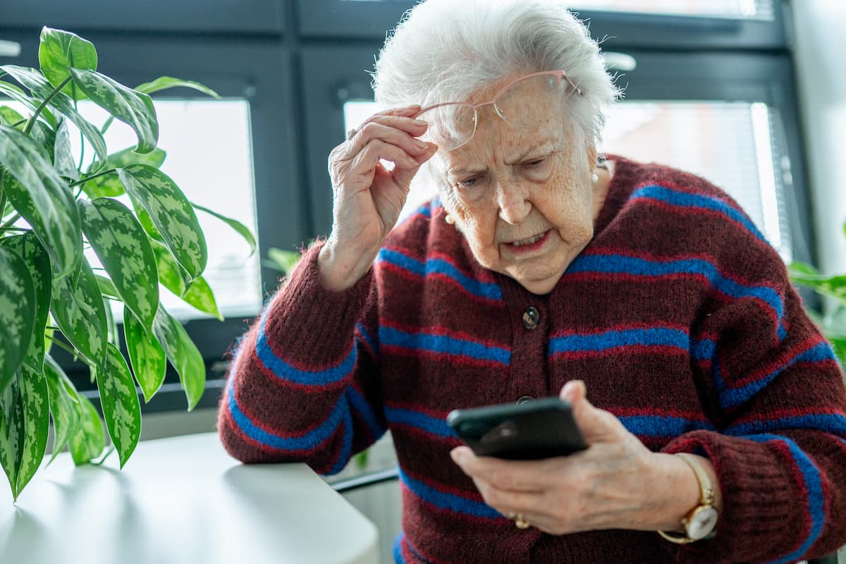 elderly woman reading a concerning message on her mobile phone