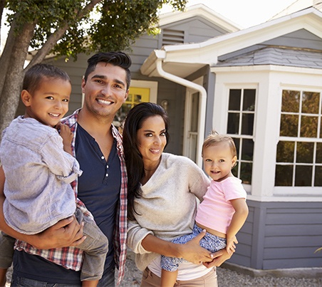 family of four in front of home