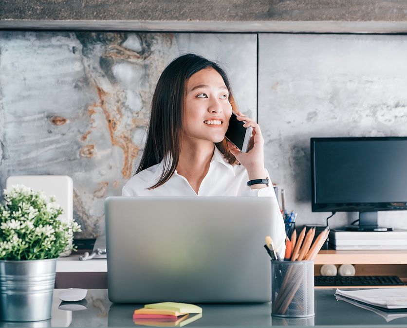 Smiling woman on phone sitting in office