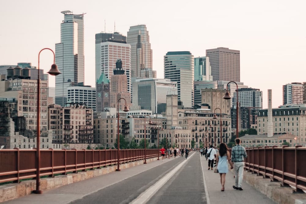 People walking on the Stone Arch Bridge with the Minneapolis skyline behind them